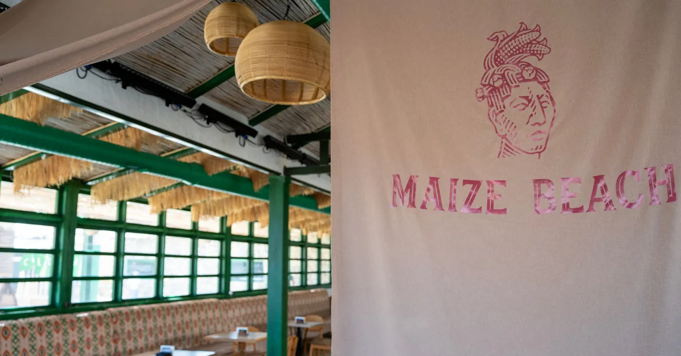 a linen banner with the MAIZE BEACH logo and woven lamps