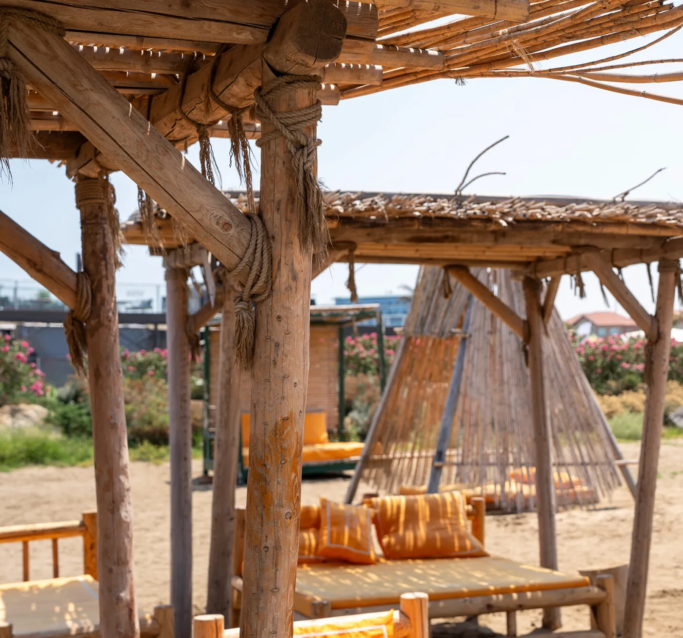 a reed hut and a daybed with orange cushions (the frame is cropped without the sign of the neighboring fast-food place)
