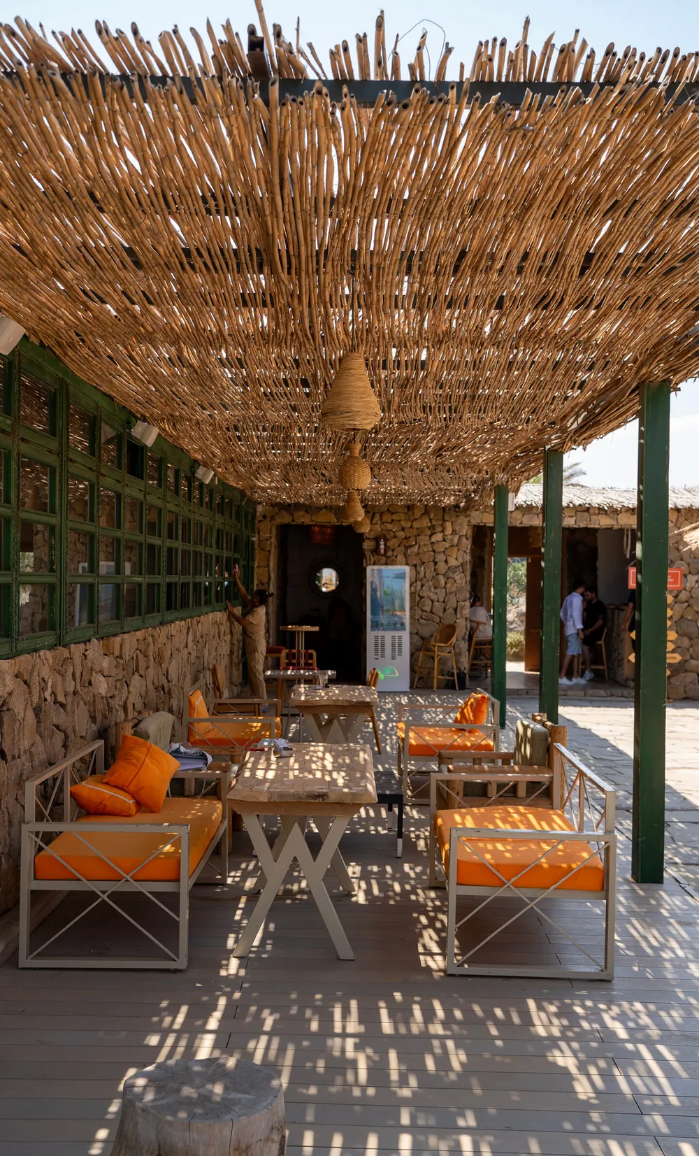 a terrace with orange sofas under a reed ceiling (vertical)