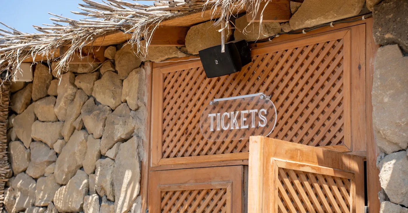 daş divar və küləş altında taxta «TICKETS» köşkü